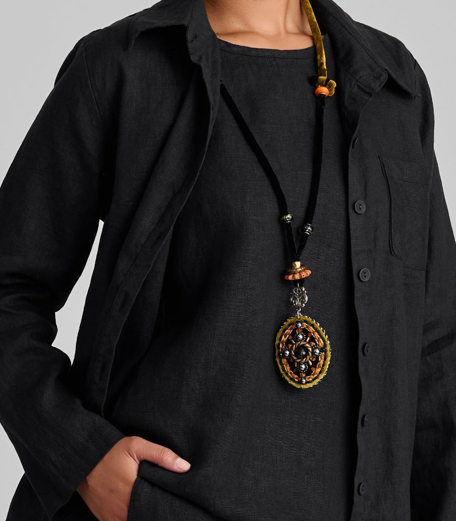 Zoom on features such as the shirt collar, chest pocket, corozo buttons, and long flowing sleeves.