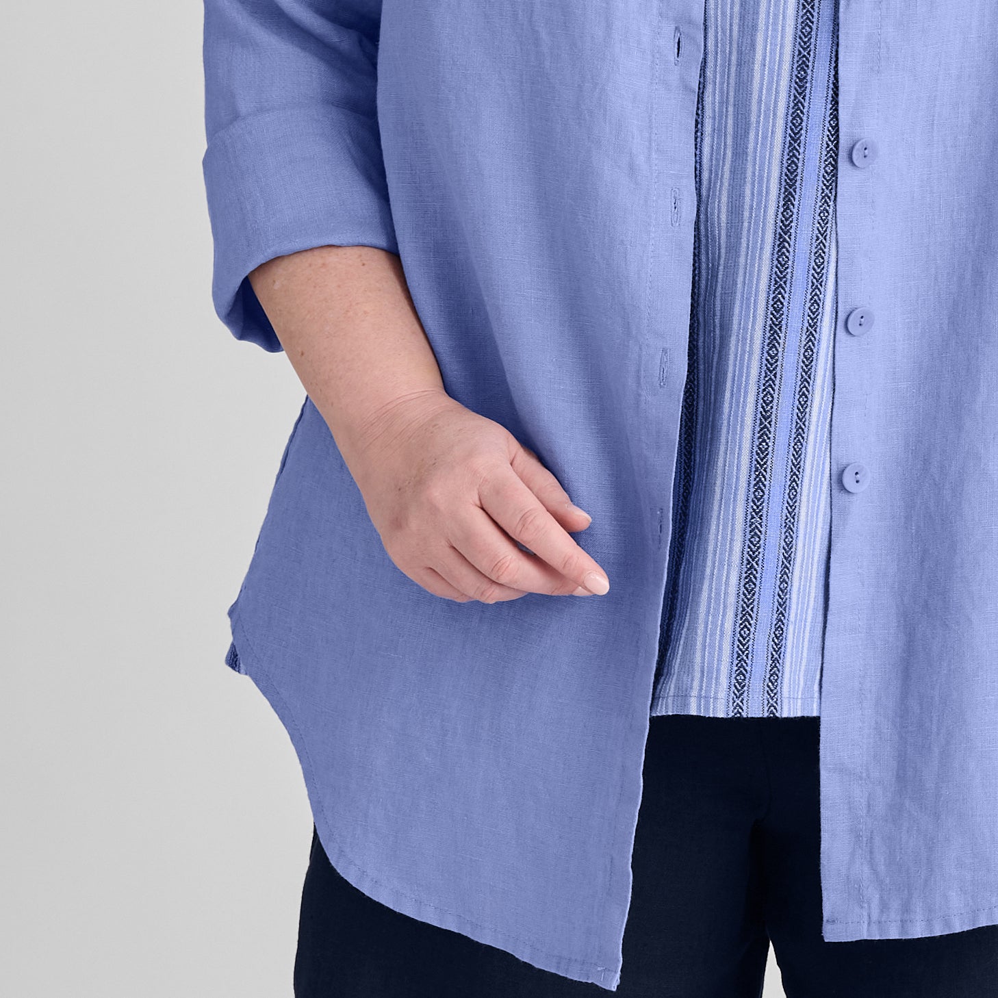 Gotcha Blouse, shown in Periwinkle, size Medium.  Close-up of the shirttail hem, rolled long sleeves, and button detail.