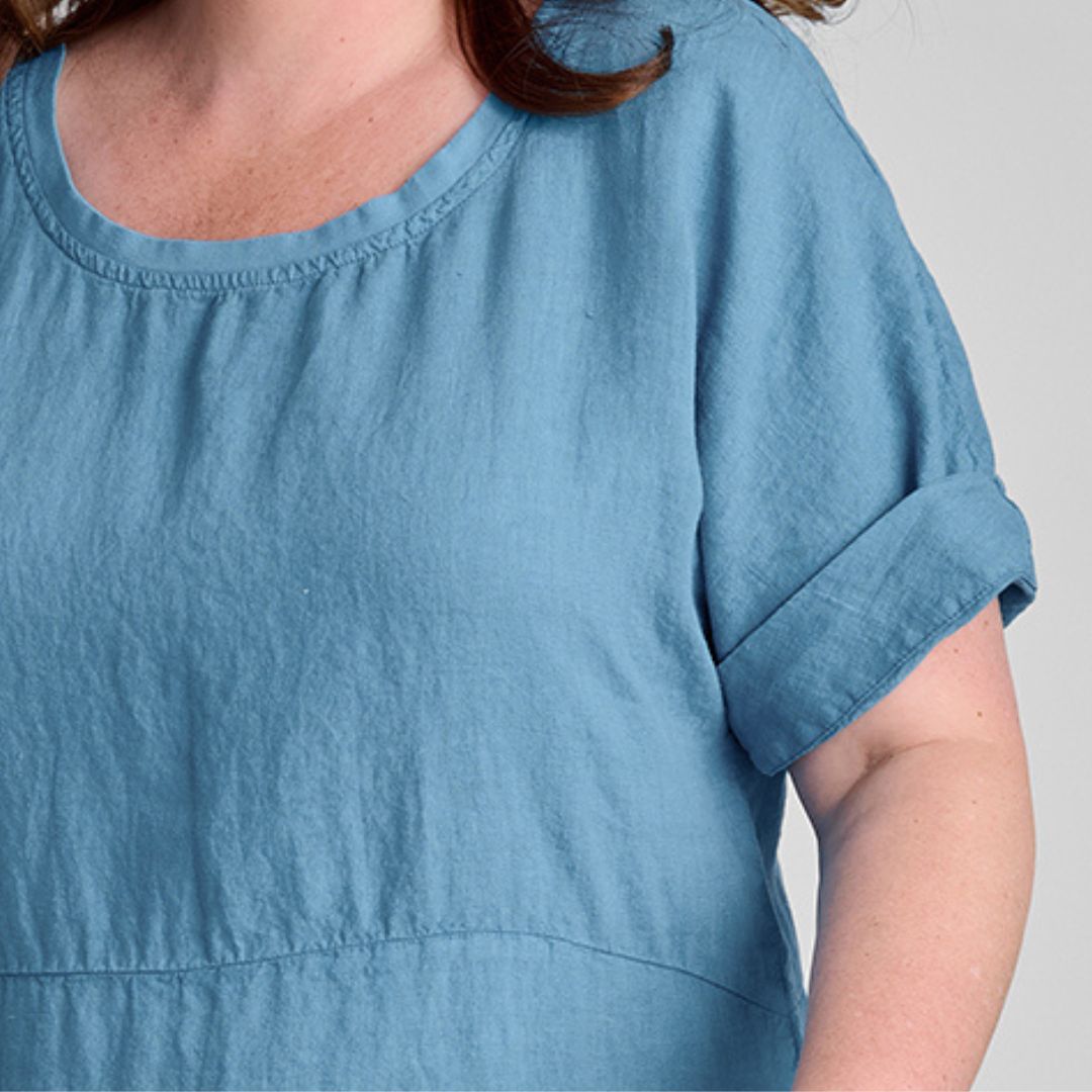 Sunny Side Dress, woven in 100% Linen (body), shown in Caribbean, size Medium. Zoom on Round Neckline with Cotton Knit trim, empire waist seam detail, elbow-length sleeves, shown with the wide hem rolled up for a shorter length.
